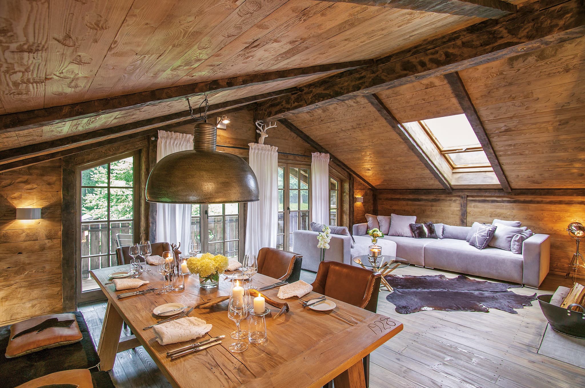 Die Alm Chalet Suite mit Wohnraum, Esstisch und Sofa — 100 m² für eine Runde von zehn