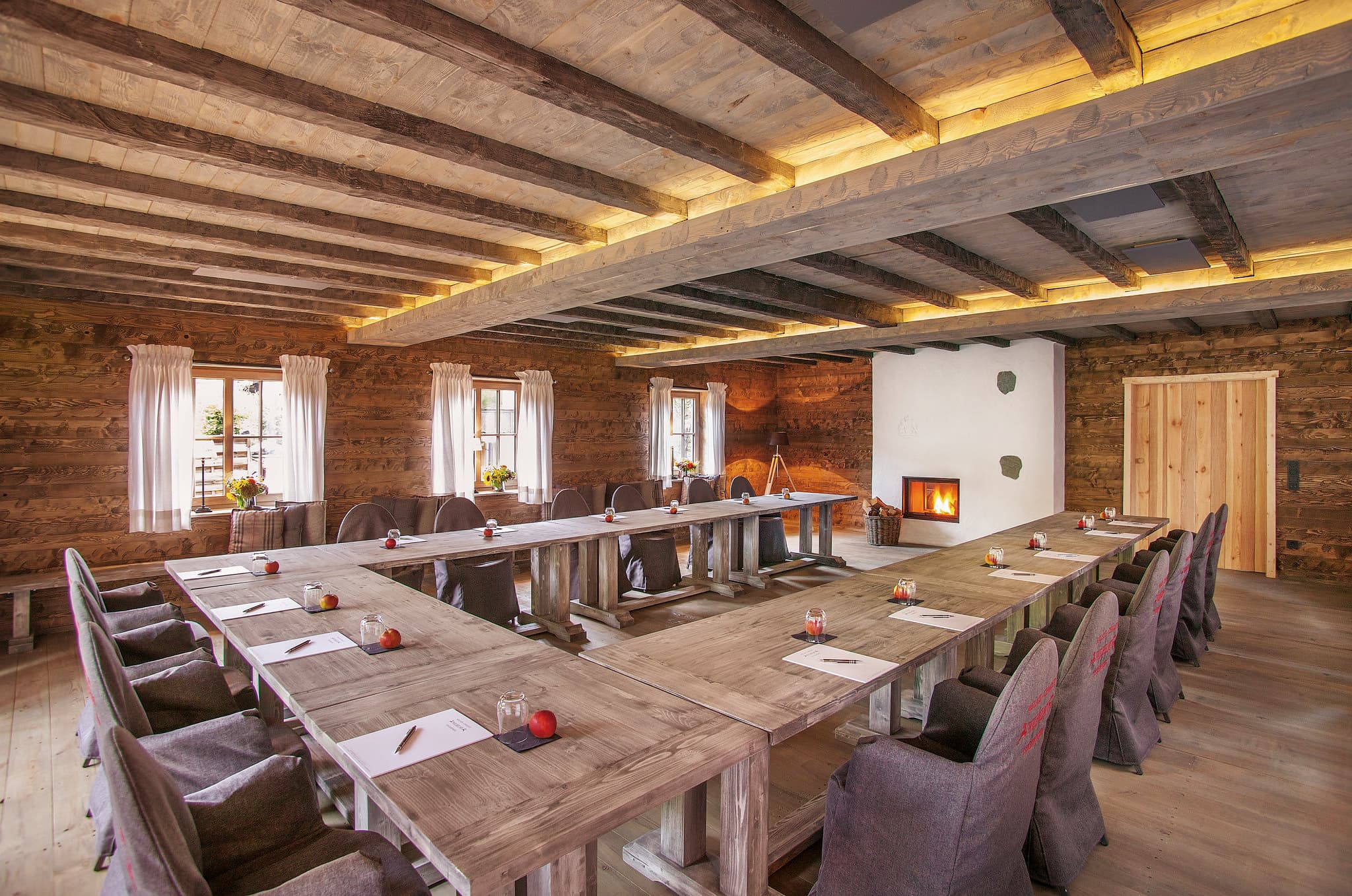 Das Alm Chalet in U-Form: Altholzbalken, offener Kamin und massive Holztische für bis zu 40 Personen
