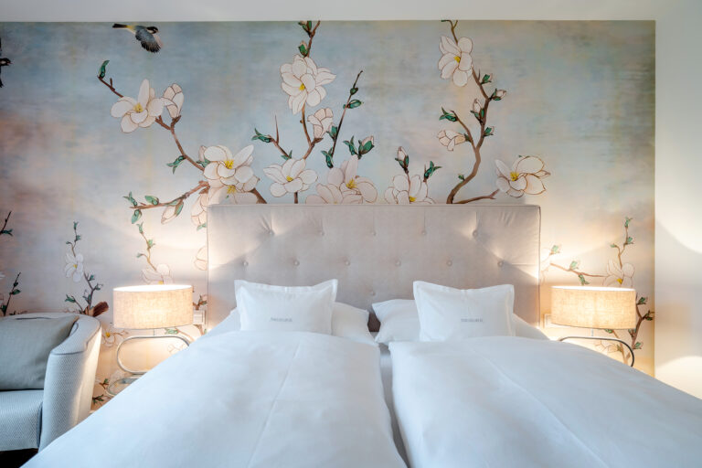 Doppelbett mit einer schönen Blumentapete an der Wand